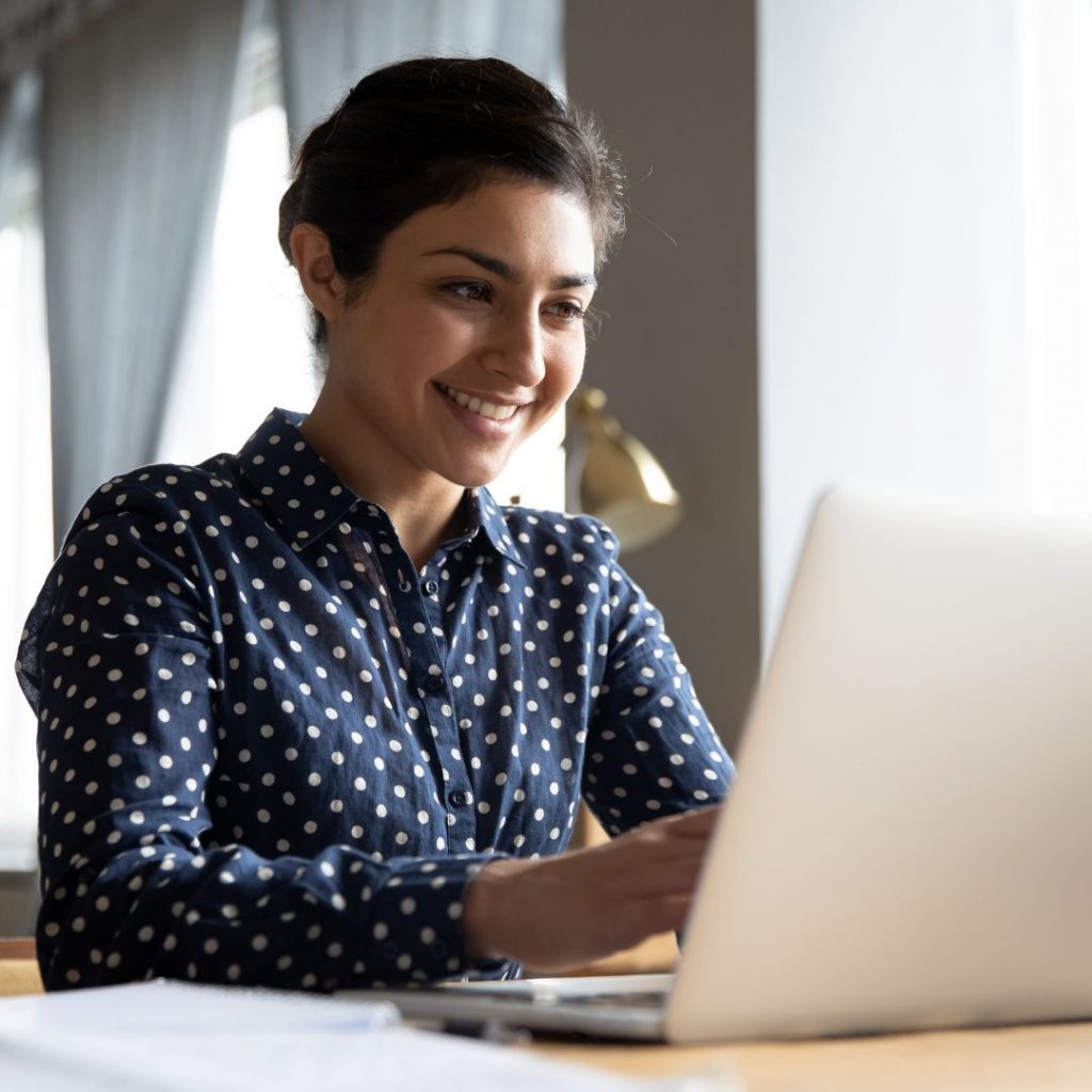 Young woman smiling and typing on her computer