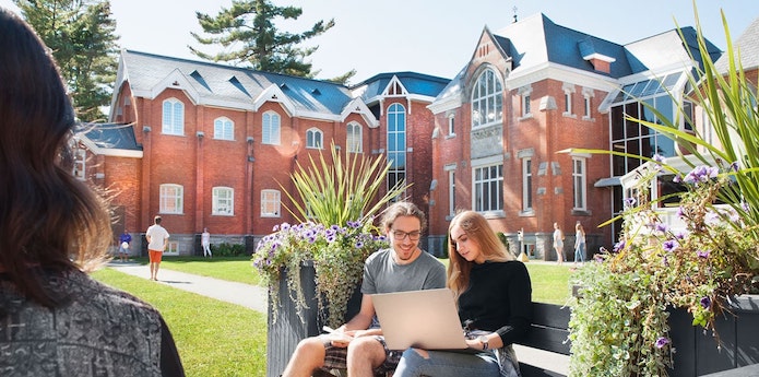 Students outdoors working on a laptop