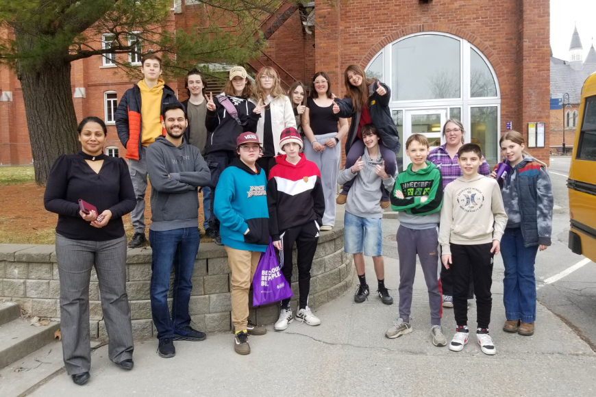 Dr. Sarathi and her 2025 workshop. A group of adults and preteens standing outside the Johnson building on Bishop's campus, near the bus stop.
