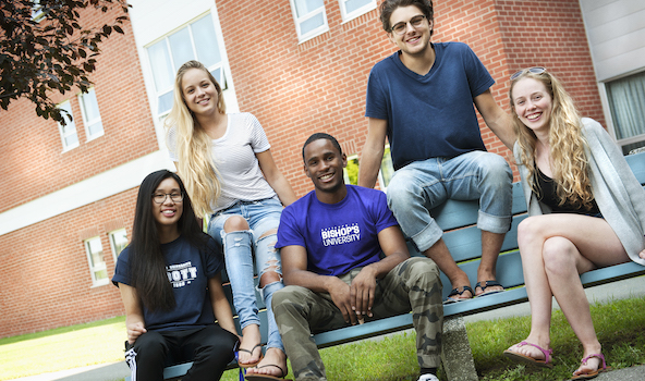 A group of students on a bench, enjoying the summer warm weather.