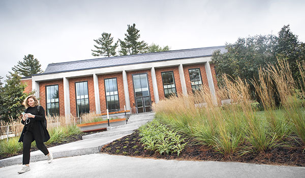 A student walking the path in front of the library learning commons.