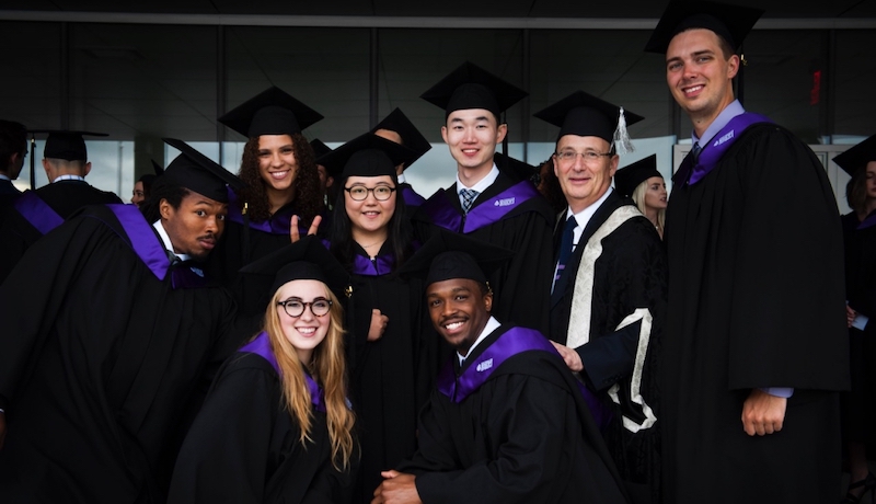 Bishop's University grads pose in their cap and gowns with the past Principal, Michael Goldbloom.