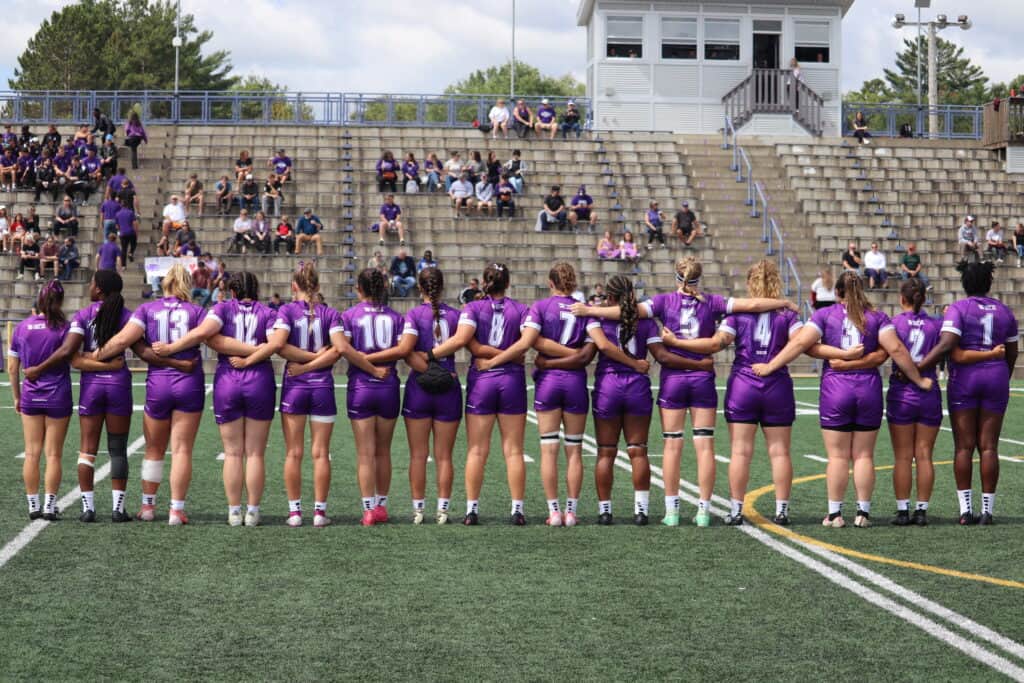 Womens Rugby team standing on coulter field.
