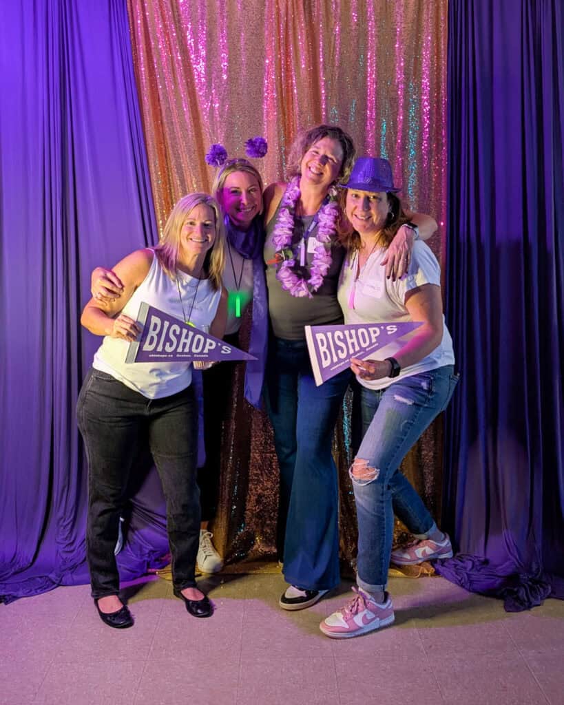 Quatre diplômées posent devant le mur du photo booth