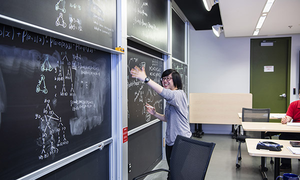 An undergrad student writing on a blackboard during the PSI START program.