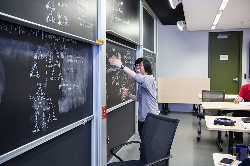 An undergrad student writing on a blackboard during the PSI START program.