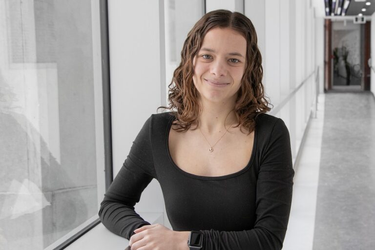 Ariane Marchand standing in a windowed hallway.