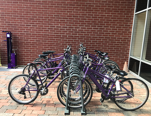Purple bicycles from the Gaiter Gears project parked in a bike rack.